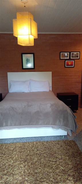Suíte com cama de casal e parede de tijolos