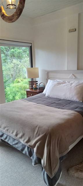 Suíte com cama de casal e janela para a mata